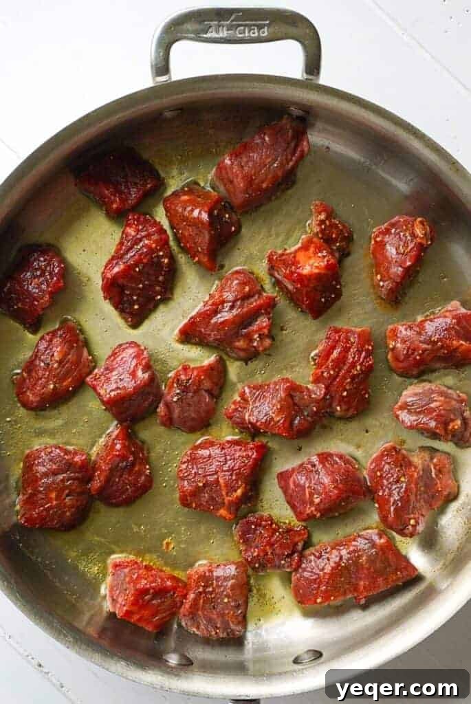 Sizzling Garlic Herb Steak Bites 4 Steak bites searing in a hot frying pan, developing a beautiful brown crust.