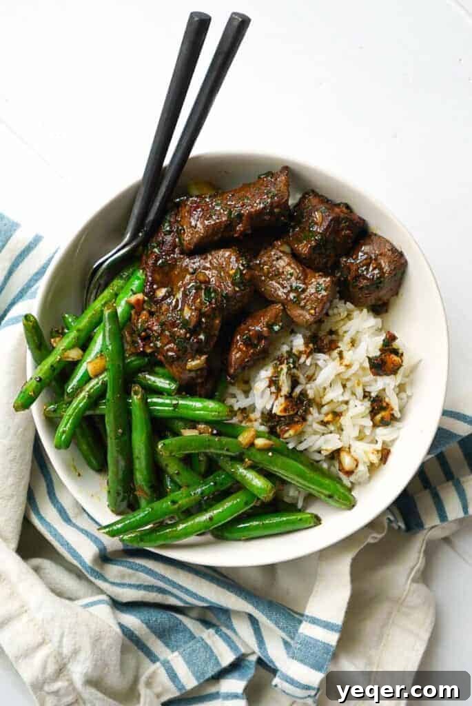 Sizzling Garlic Herb Steak Bites 8 A bowl of Garlic Herb Steak Bites served alongside a fresh green bean side dish.