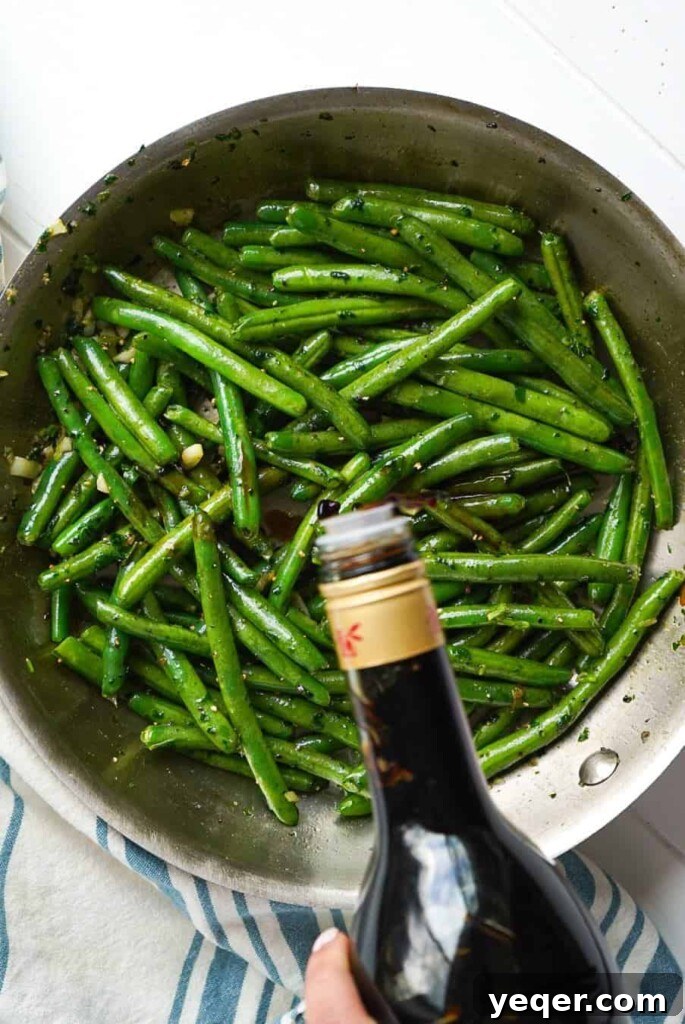 Zesty Moroccan Green Beans 3 A glug of balsamic vinegar going into a pan of green beans, creating a flavorful sauce.