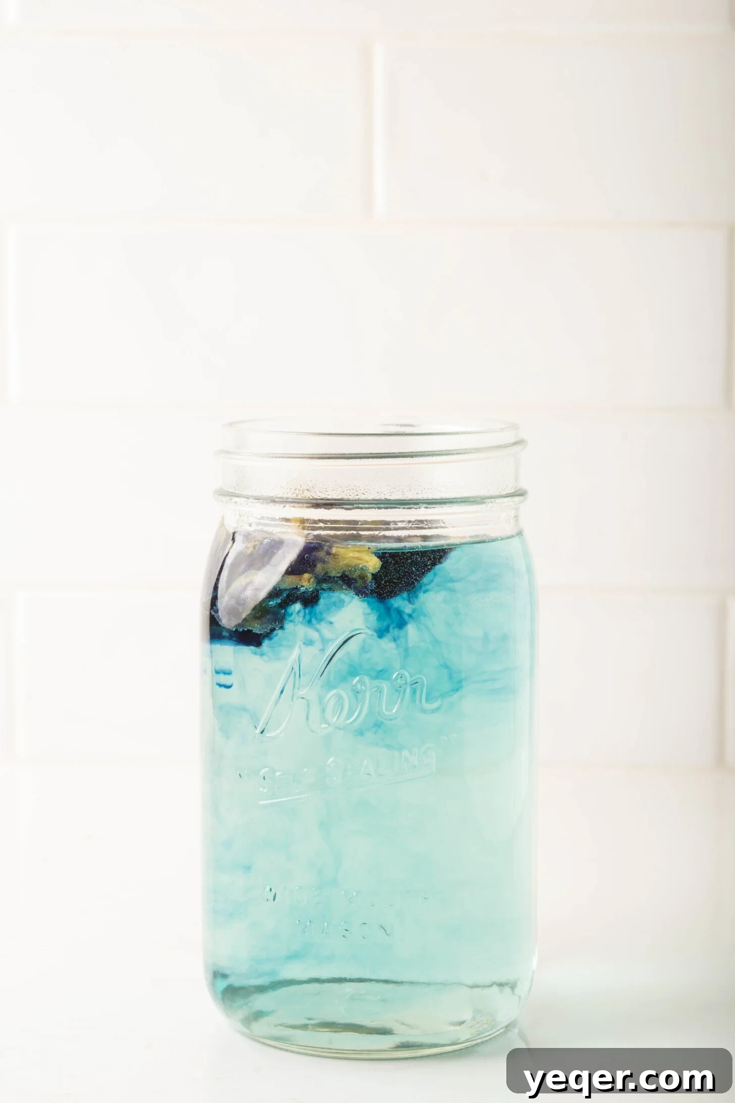 Indigo Bloom Delight 4 Dried butterfly pea flowers steeping in hot water within a glass pitcher, creating a deep blue infusion.