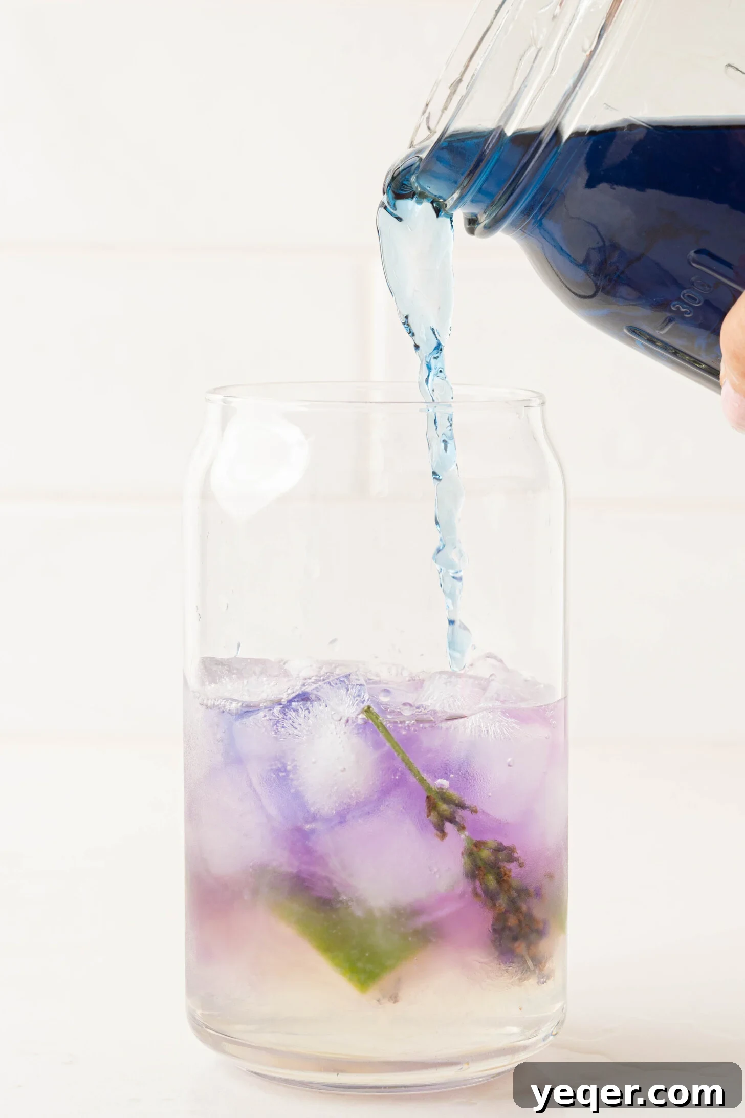 Indigo Bloom Delight 6 The dark blue butterfly pea flower tea being carefully poured into a glass already containing ice and other ingredients, initiating the color change.