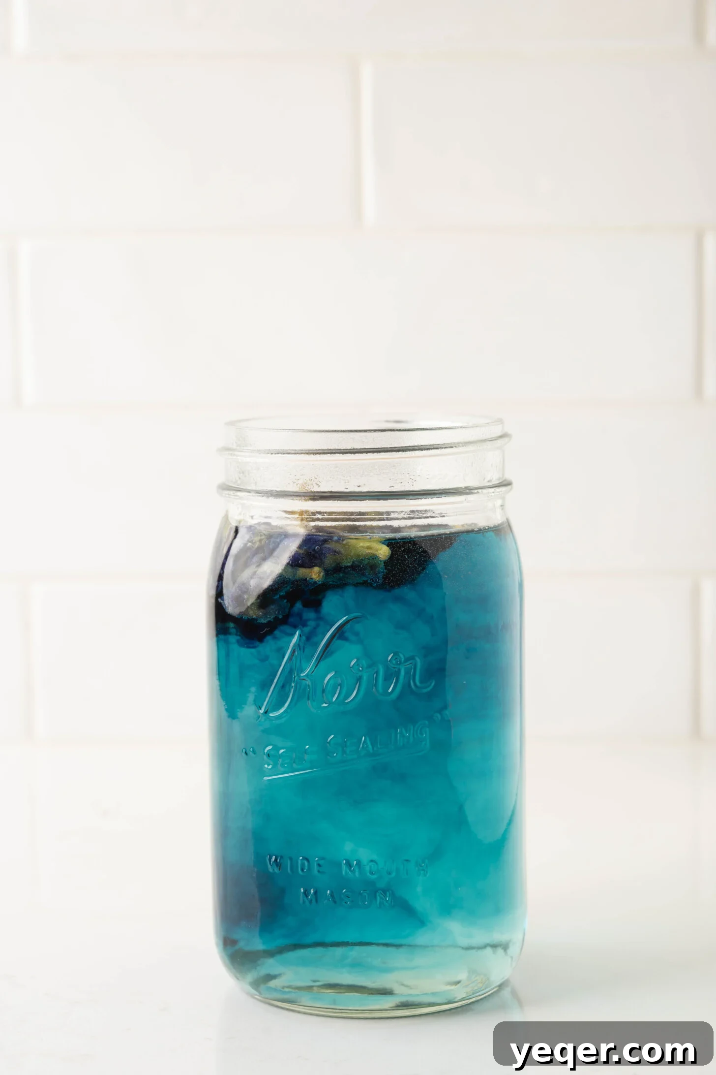 Indigo Bloom Delight 9 A glass pitcher filled with the deep blue infusion of butterfly pea flower tea, ready for cocktail preparation.