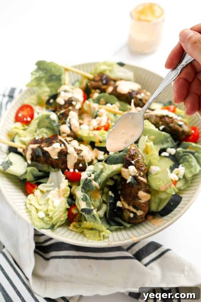 Moroccan Kefta Salad Bowl 7 Harissa yogurt dressing drizzling on a Moroccan burger salad.