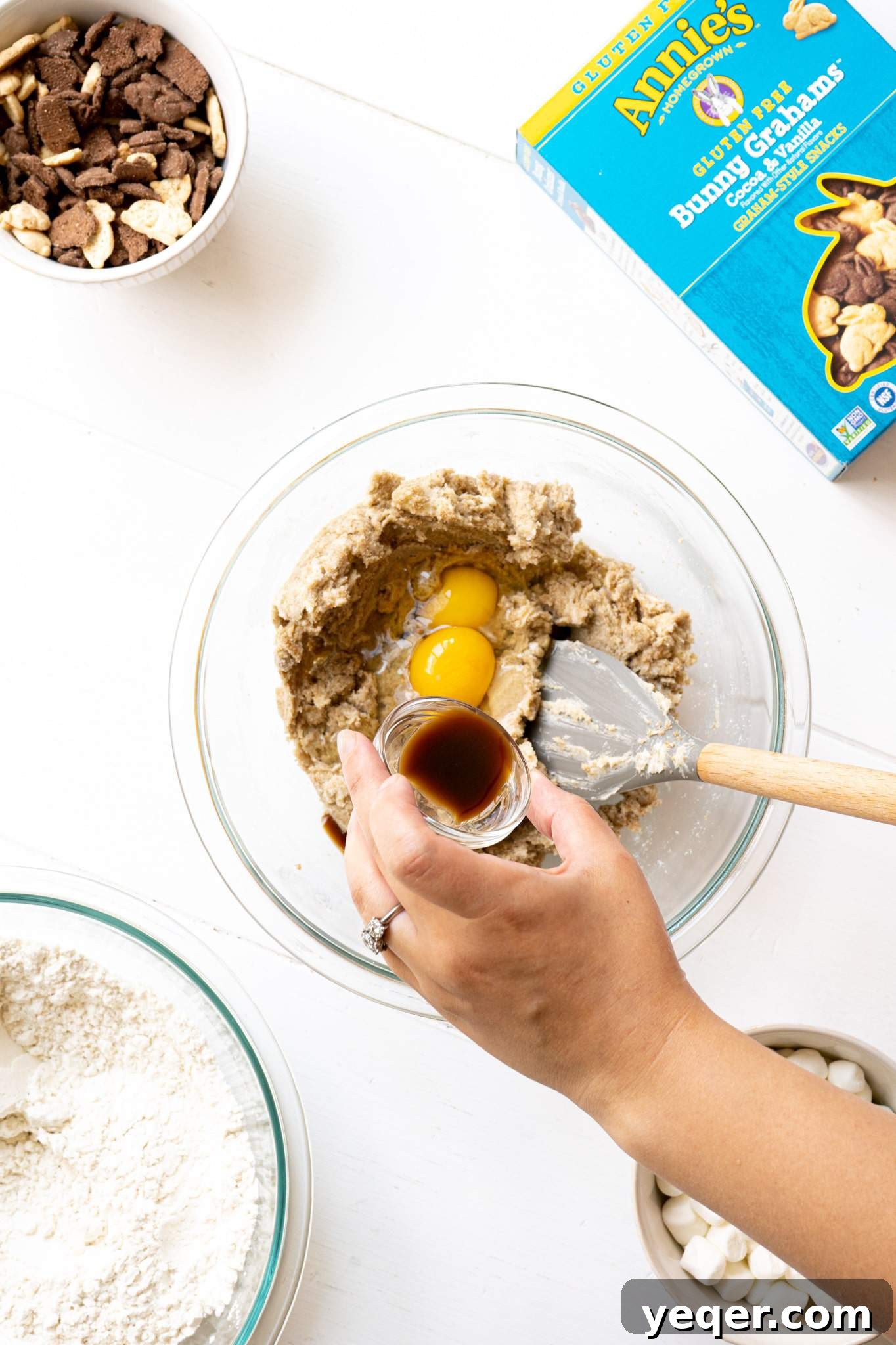Gluten Free Smores Cookies with Annies and The Feed Feed 5 A hand pouring vanilla into cookie dough with eggs.