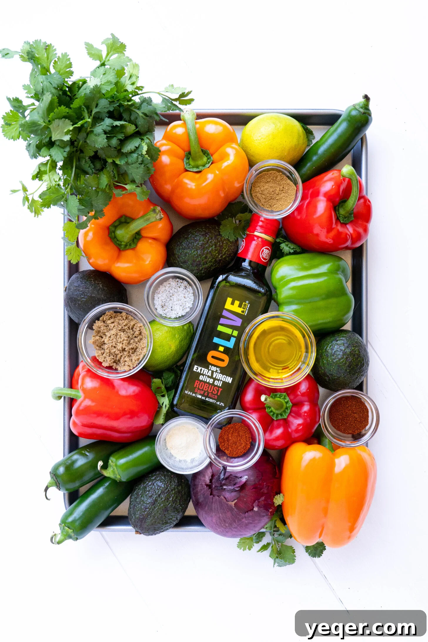 Effortless Sheet Pan Steak Fajitas 3 A sheet pan with colorful bell peppers, sliced onions, and a jalapeño, coated in spices and olive oil, ready for the oven.