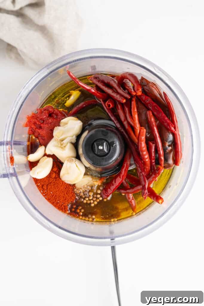 Unlocking Moroccan Flavor with Homemade Harissa 5 All harissa ingredients, including rehydrated chiles, garlic, spices, and olive oil, loaded into a food processor.