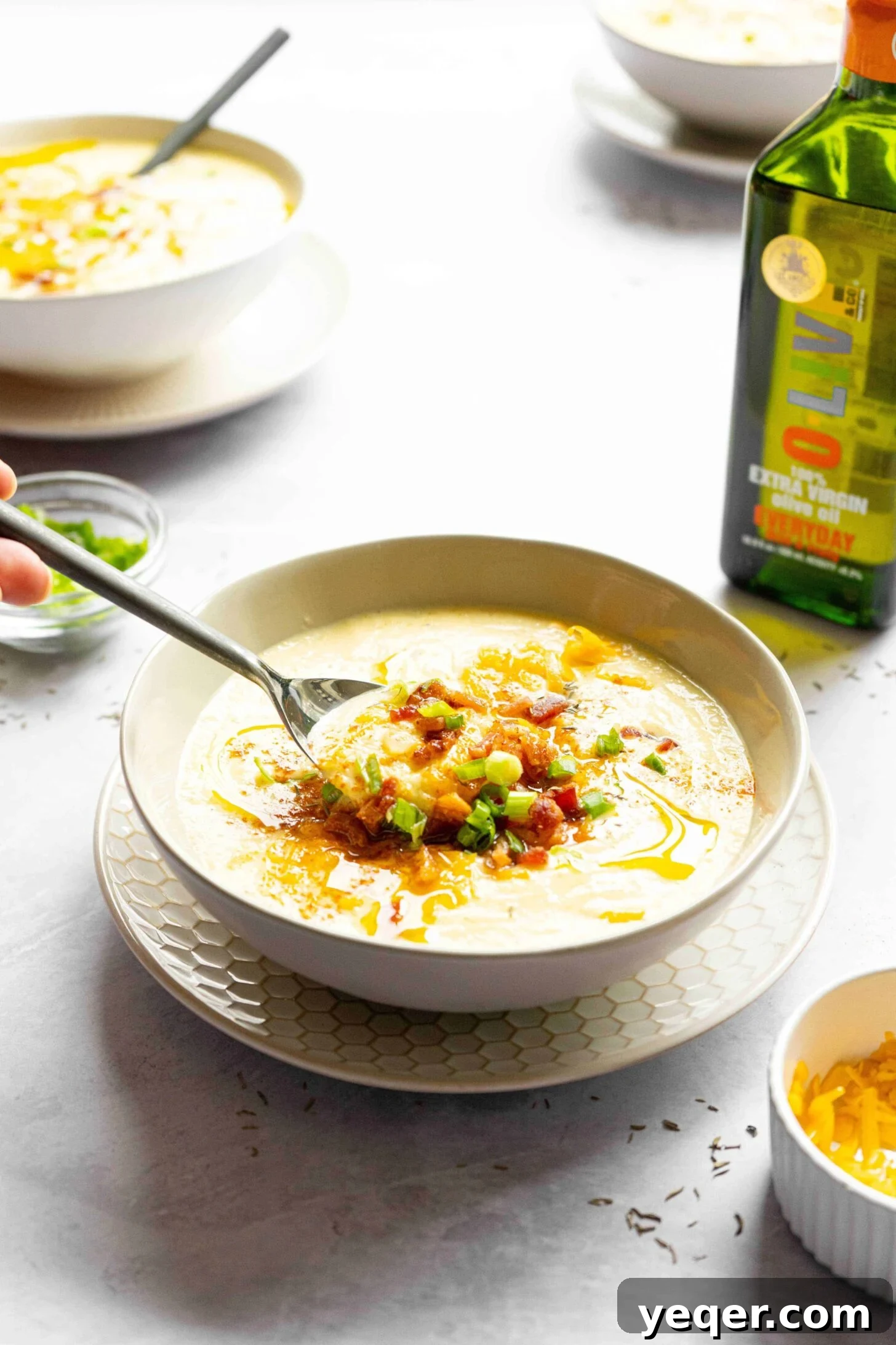 Decadent Loaded Cauliflower Dream 8 A spoon scooping up a portion of creamy cauliflower soup, showcasing its rich texture.