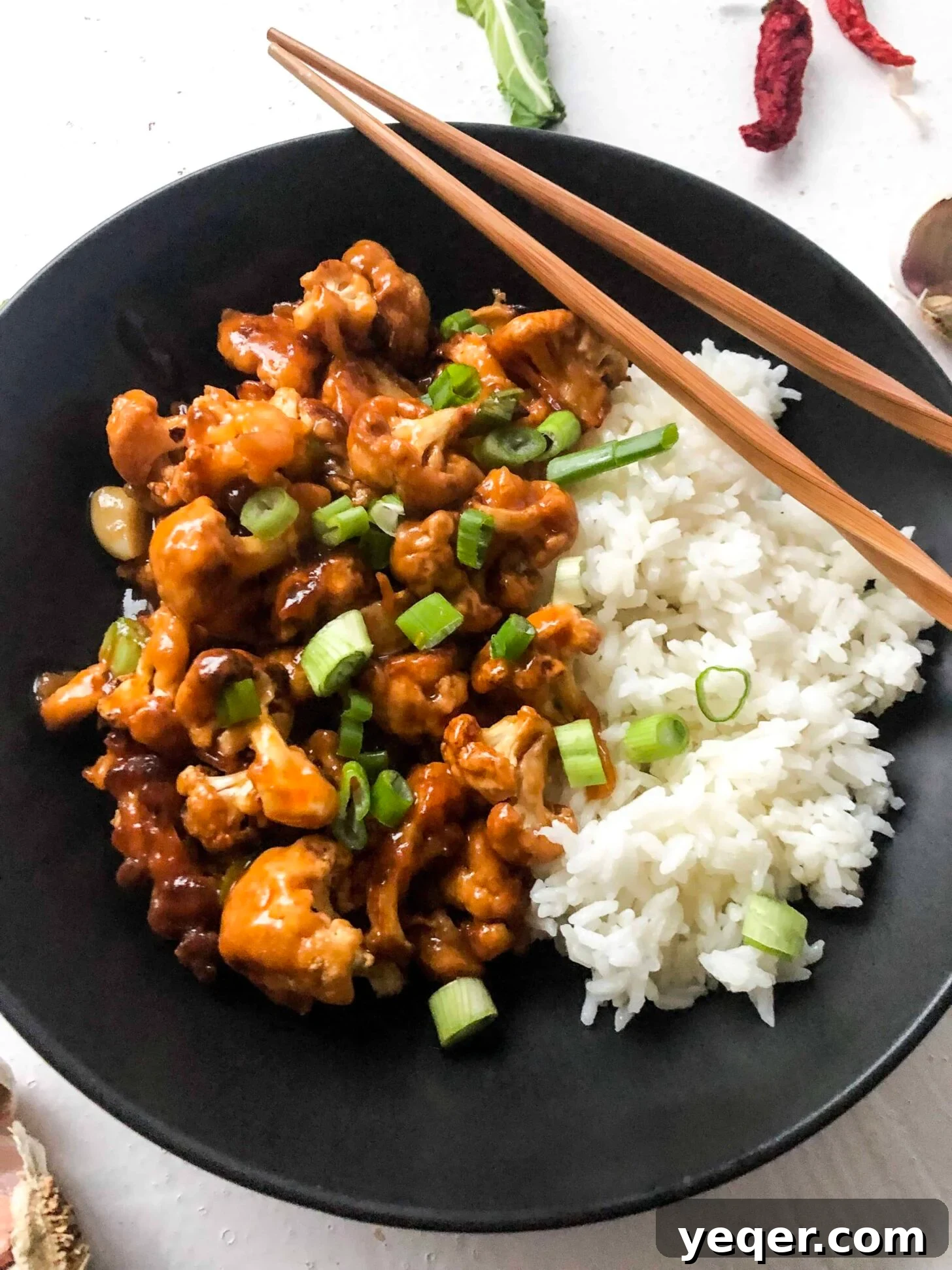 Zesty Orange Glazed Cauliflower Vegan Gluten-Free 4 A close-up bowl of crispy asian inspired orange cauliflower garnished with sesame seeds and green onions.