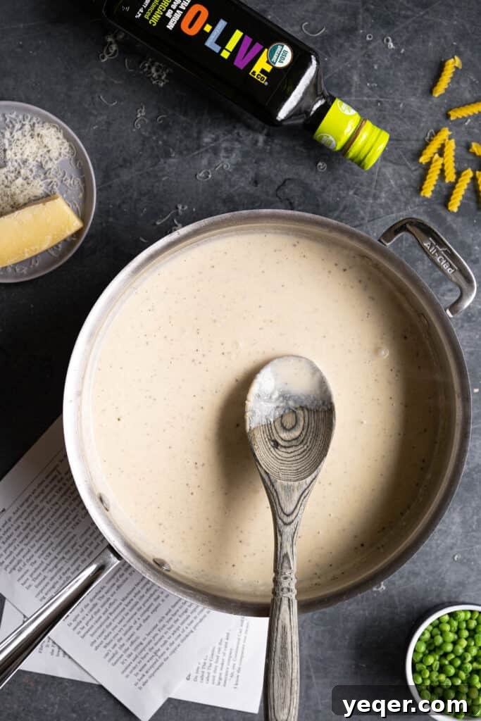 Savory Mushroom Medley Pasta 7 A creamy white sauce being whisked in a pot on the stovetop.