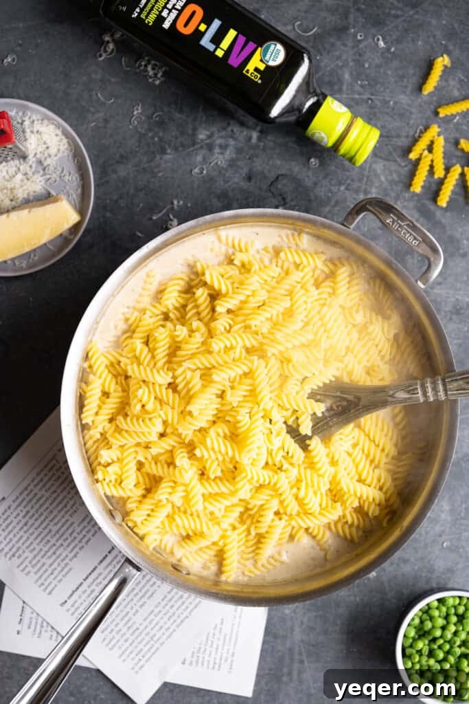 Savory Mushroom Medley Pasta 8 Cooked pasta being added to a pan filled with creamy sauce.