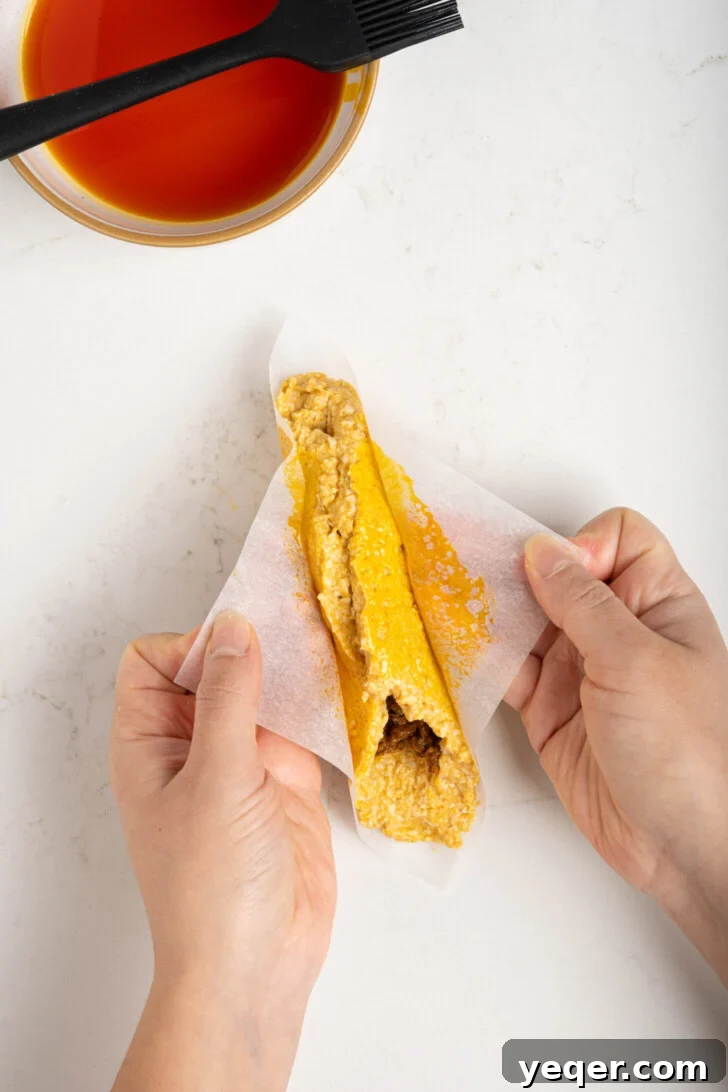 Homemade Alcapurrias: A Taste of Puerto Rico 11 Alcapurrias being carefully folded and sealed with parchment paper.