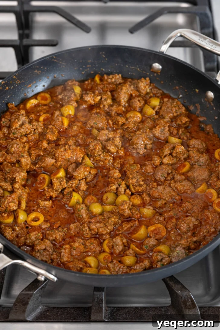 Homemade Alcapurrias: A Taste of Puerto Rico 7 Ground beef and sofrito simmering in a pan, forming the picadillo filling.