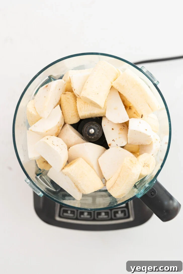 Homemade Alcapurrias: A Taste of Puerto Rico 8 Peeled taro and green bananas being processed in a food processor to make masa.