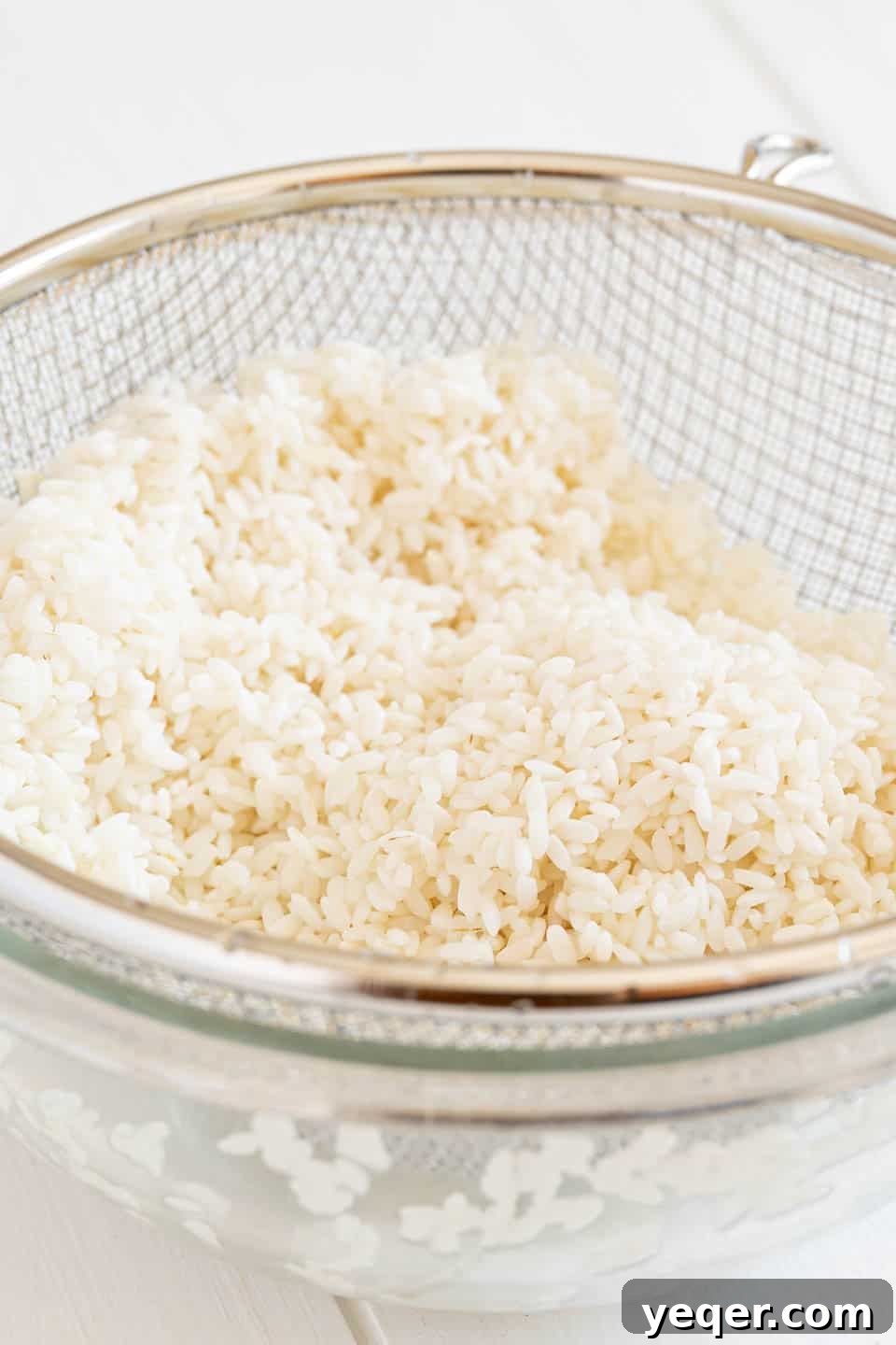 Creamy Coconut Rice Pudding 4 A close-up of short-grain rice in a fine-mesh strainer after soaking, ready for cooking.