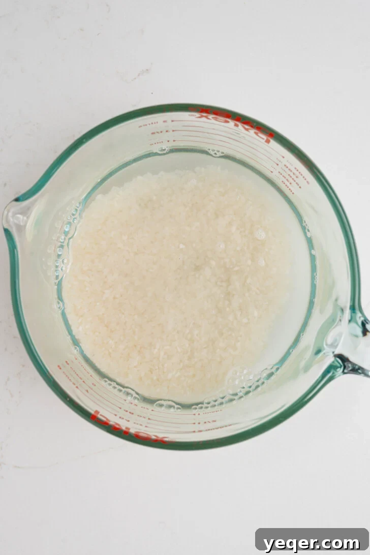 Creamy Coconut Rice Pudding 3 Rice soaking in water in a clear bowl, a crucial step for perfect Arroz con Dulce.