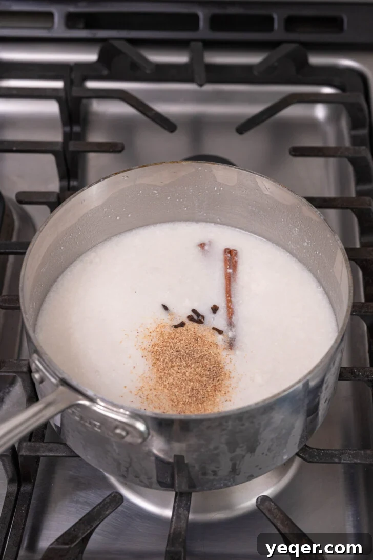 Creamy Coconut Rice Pudding 8 Coconut milk with whole spices simmering in a pot.