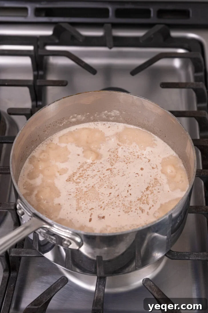 Creamy Coconut Rice Pudding 10 Coconut rice pudding simmering gently in a pot with the lid slightly ajar.