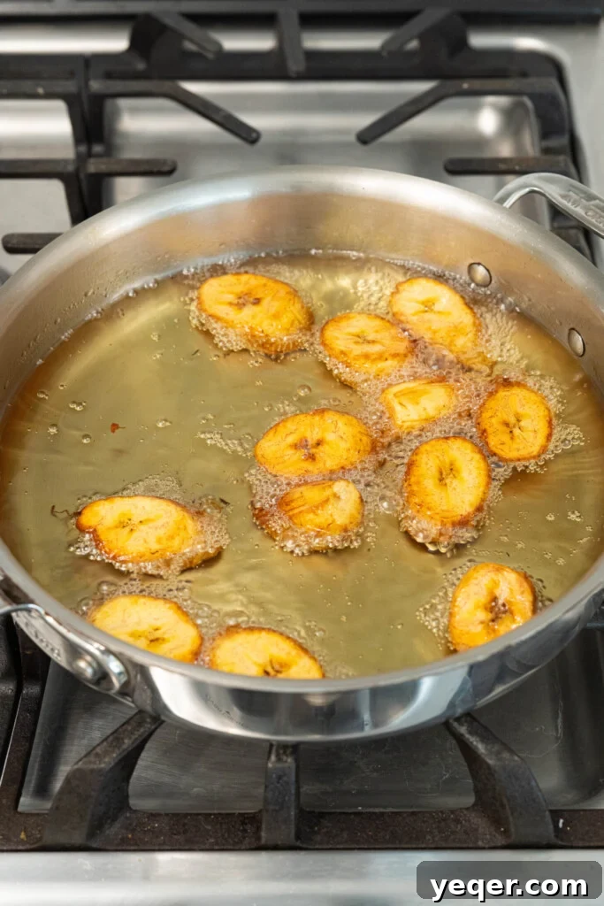 Caramelized Golden Plantains 8 Frying plantains being flipped to achieve an even golden-brown color.
