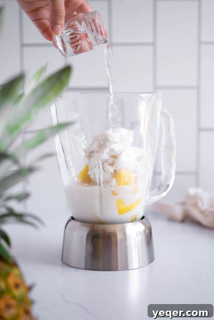 Pink Pina Perfection 4 A shot of sparkling silver rum being carefully poured from a jigger into a high-powered blender, joining the other tropical ingredients to add an alcoholic kick to the cocktail.