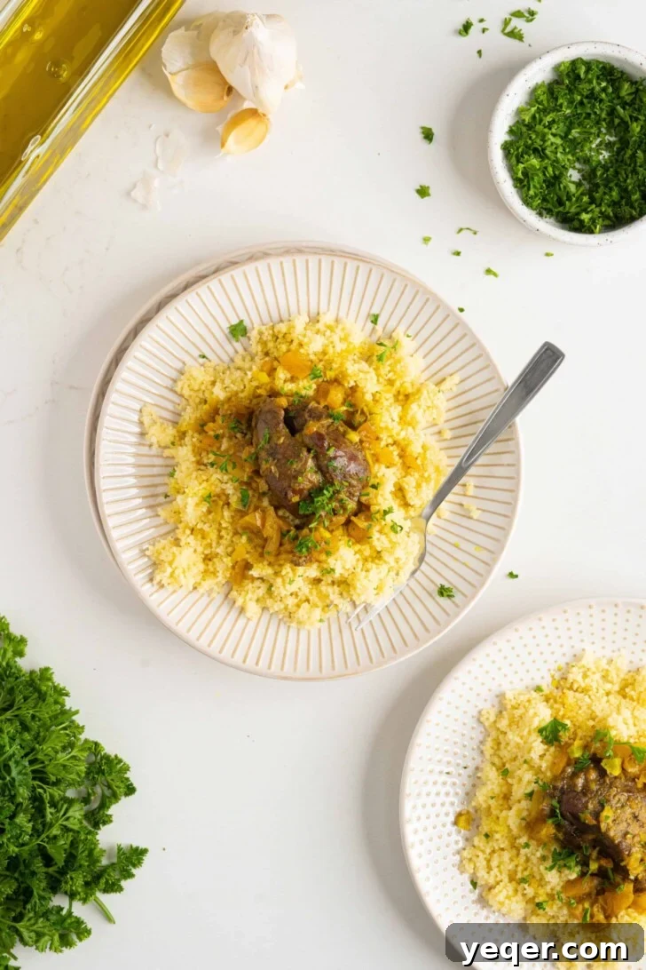 Authentic Moroccan Tangia Lamb Shank Tagine 7 A serving of Moroccan lamb shank tagine on a plate, garnished with fresh parsley and served with a side of couscous.