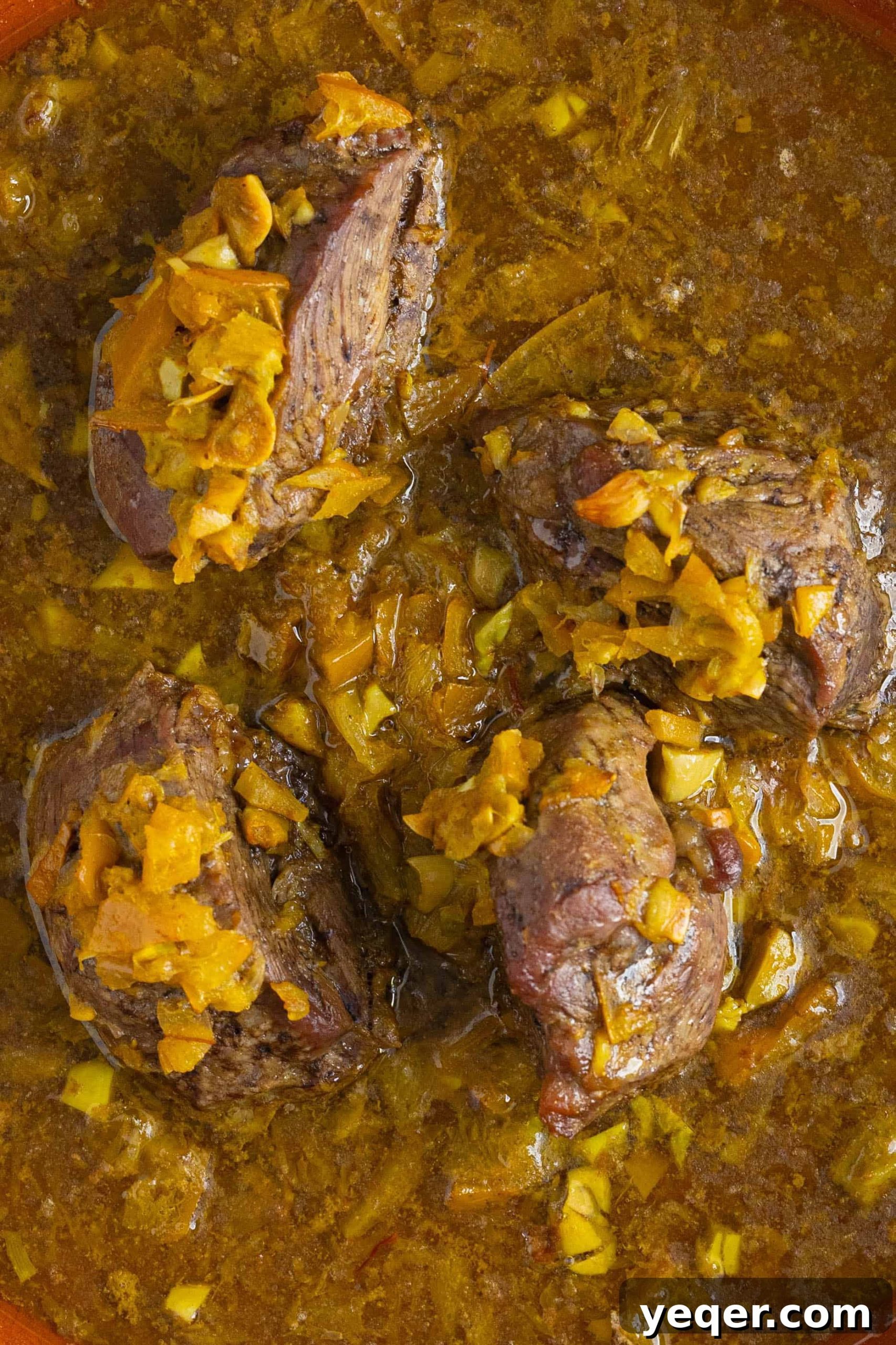 Authentic Moroccan Tangia Lamb Shank Tagine 8 Close-up of tender lamb shanks simmering in a rich Moroccan sauce within a tagine pot.