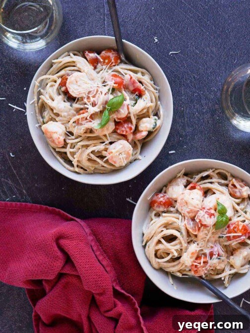 Two bowls of gluten free shrimp carbonara, garnished with fresh basil and parmesan.