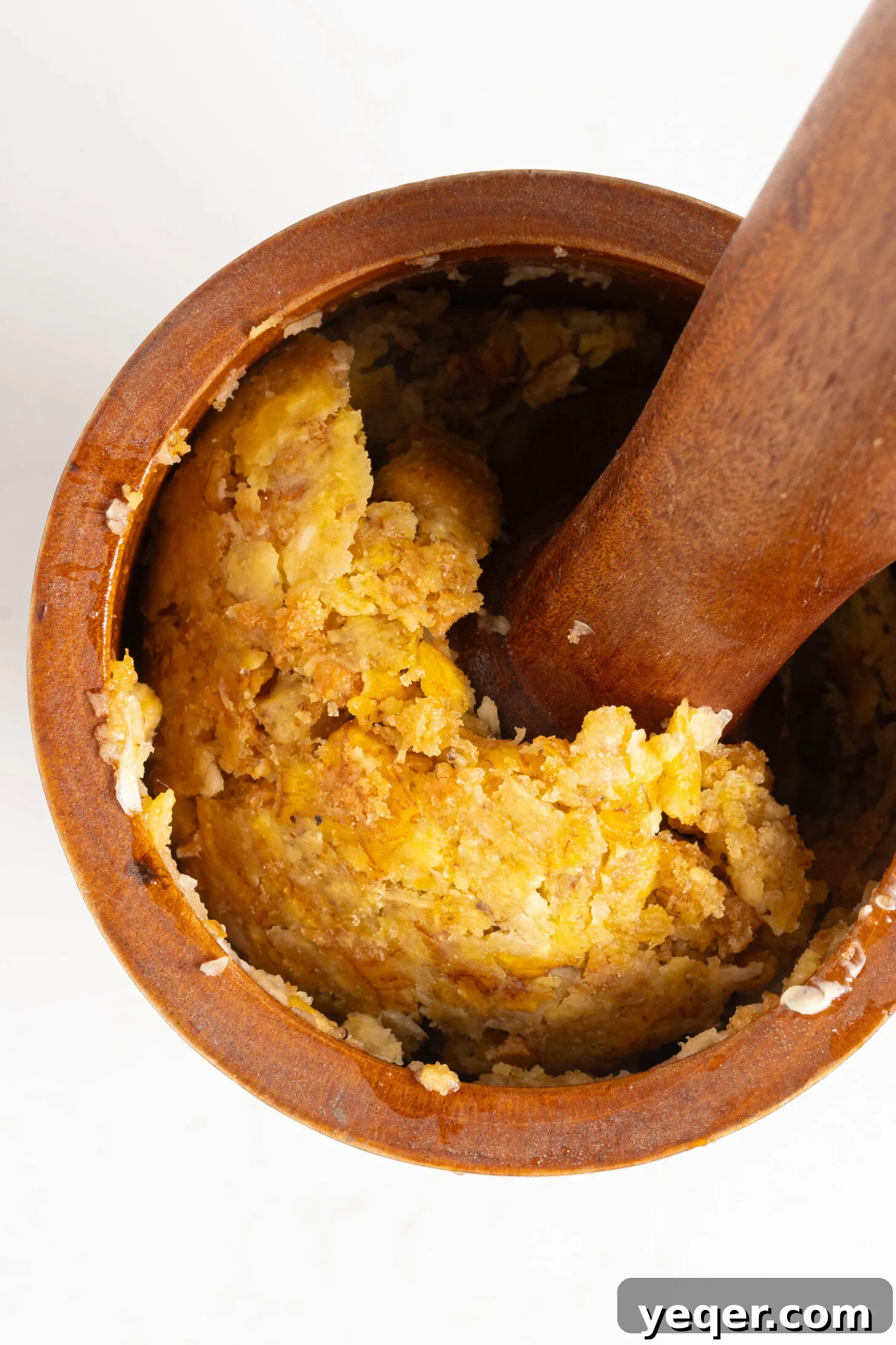 25 Dakikada Geleneksel Porto Riko Mofongosu 3 A traditional wooden pilon (mortar and pestle) filled with freshly mashed Mofongo, showcasing its rustic texture.