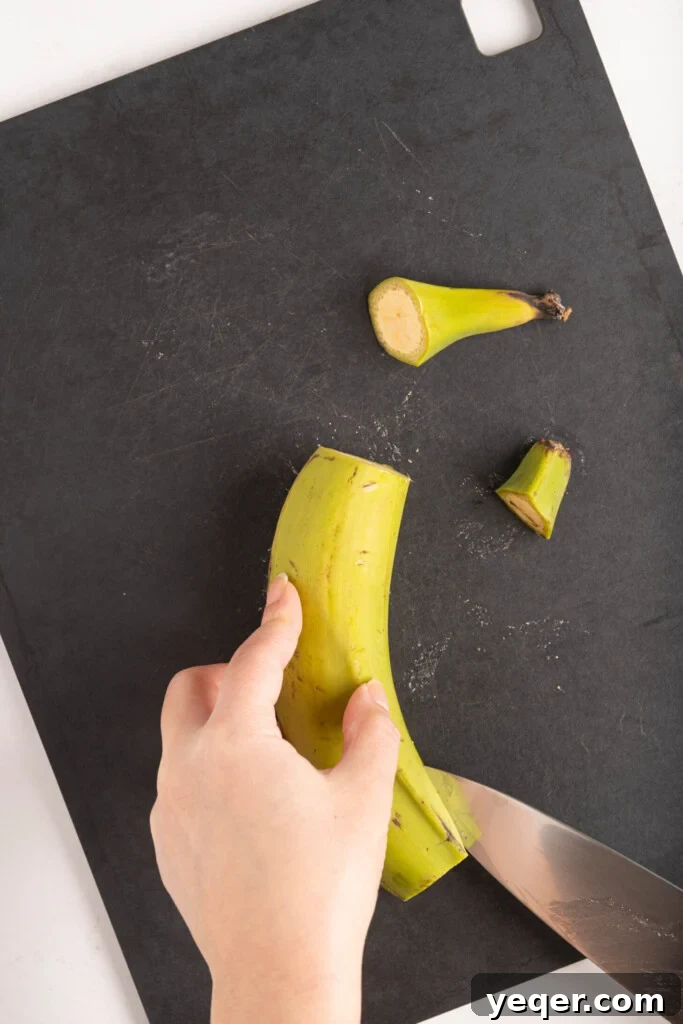 25 Dakikada Geleneksel Porto Riko Mofongosu 5 The initial step of preparing plantains for Mofongo: expertly cutting the tip off a green plantain.