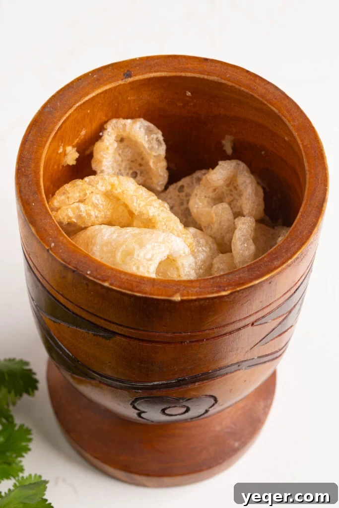 25 Dakikada Geleneksel Porto Riko Mofongosu 8 A mortar and pestle filled with crunchy chicharrones, ready to be mashed into the Mofongo mixture.