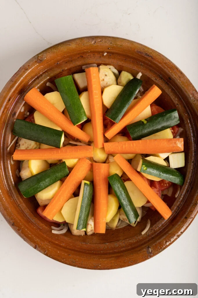 Spiced Moroccan Potato and Vegetable Tagine 11 An exquisitely assembled vegetable tagine, artfully arranged with concentric layers of sliced potatoes, carrots, and zucchini over a flavorful bed of sautéed aromatics, before going into the oven.
