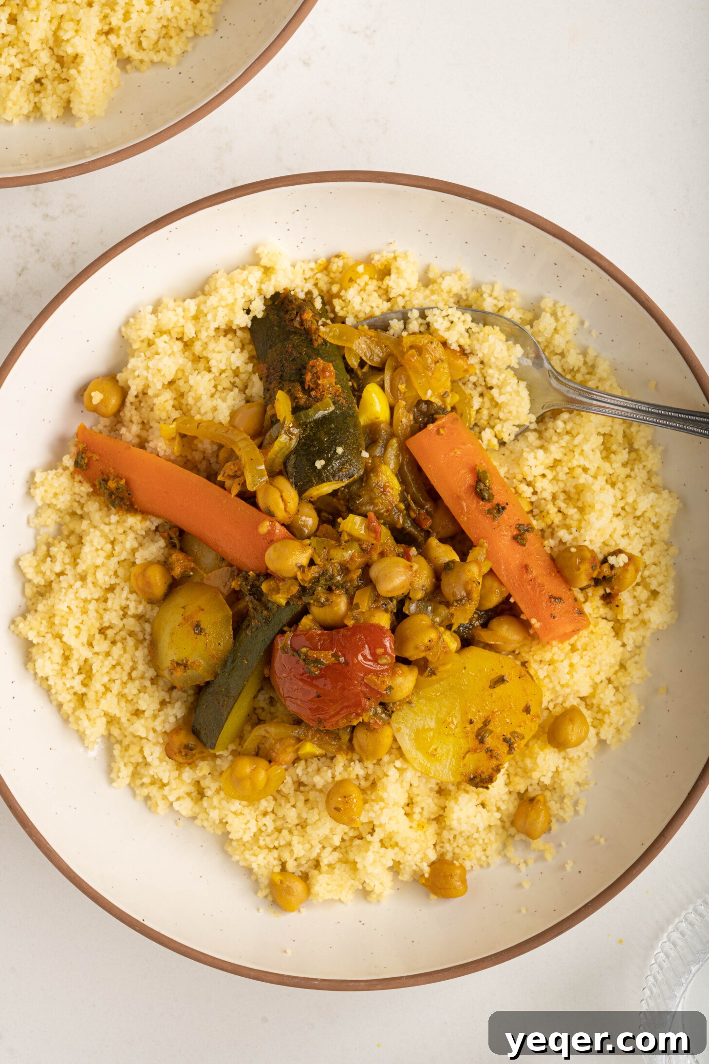 Spiced Moroccan Potato and Vegetable Tagine 14 A beautifully plated bowl of Moroccan vegetable tagine served over a bed of fluffy couscous, garnished with fresh herbs, showcasing a complete and inviting, plant-based meal.