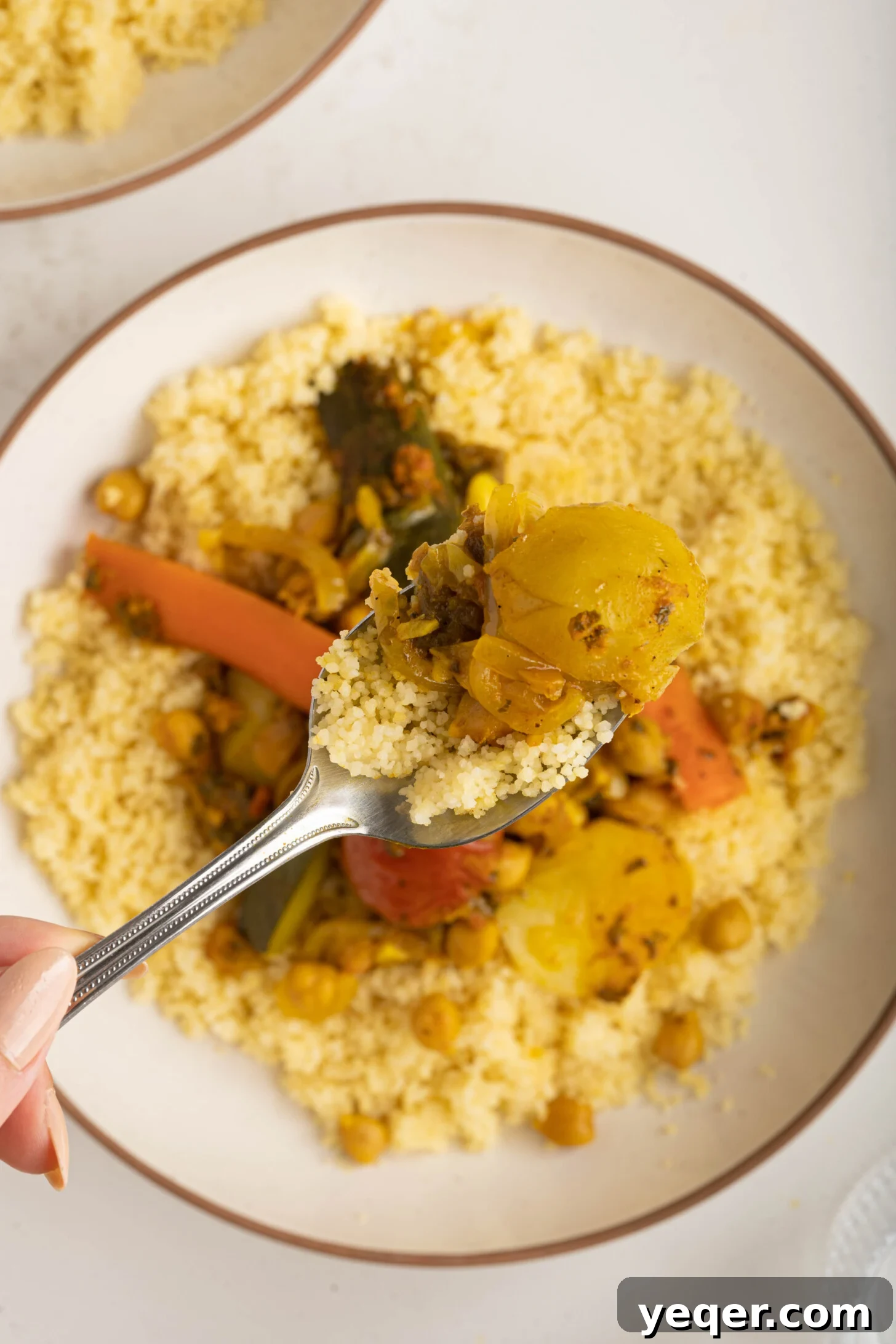 Spiced Moroccan Potato and Vegetable Tagine 15 A close-up shot of a spoon laden with fluffy couscous and tender Moroccan vegetable tagine, perfectly portioned and ready for a delicious bite, highlighting the texture and richness of the dish.