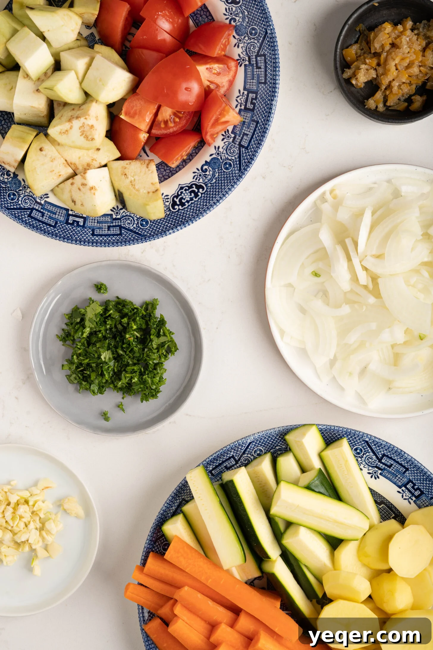 Spiced Moroccan Potato and Vegetable Tagine 4 Plates displaying neatly chopped eggplant, carrots, zucchini, and other fresh vegetables, meticulously prepared and ready for cooking in a tagine pot.