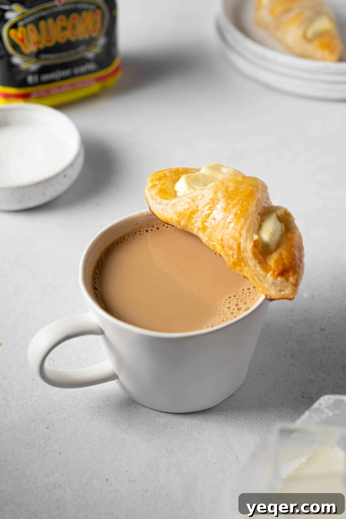 A cup of Puerto Rican Café con Leche served with a flaky, golden-brown Quesito pastry, perfect for breakfast or a snack.