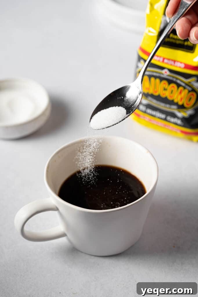 Sugar granules being poured into a mug of freshly brewed coffee, illustrating the customization of sweetness.