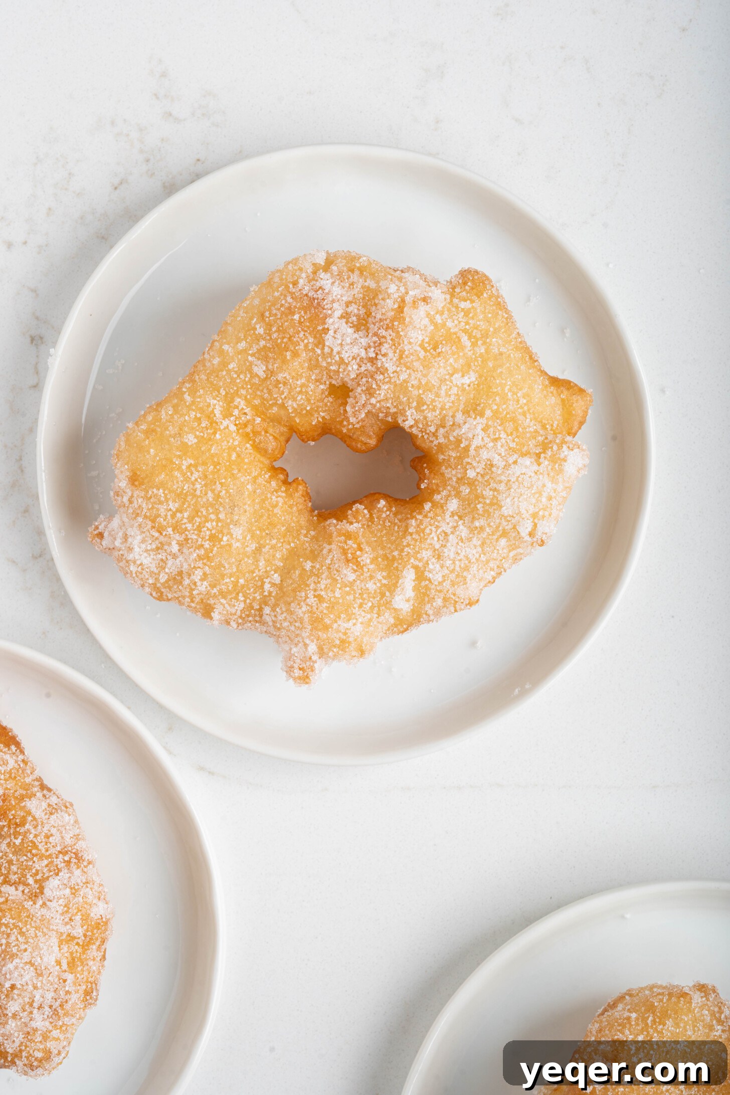 Sfenj: Moroccan Spongy Delights 10 A single perfectly golden and spongey Moroccan Sfenj donut resting on a white plate, showcasing its texture.