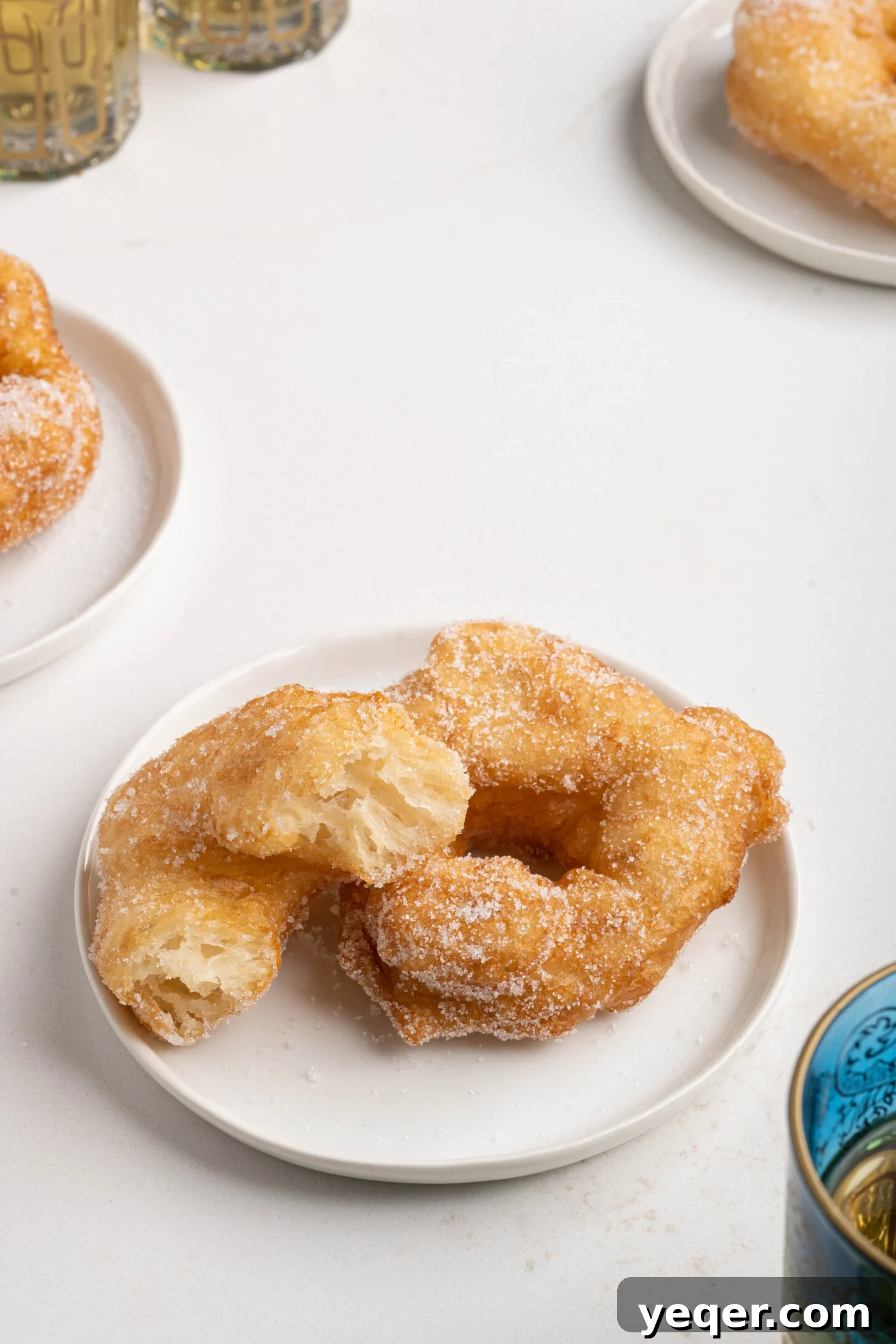 Sfenj: Moroccan Spongy Delights 11 Two enticing Moroccan Sfenj donuts on a plate, one plain and one lightly sugared, ready for serving.