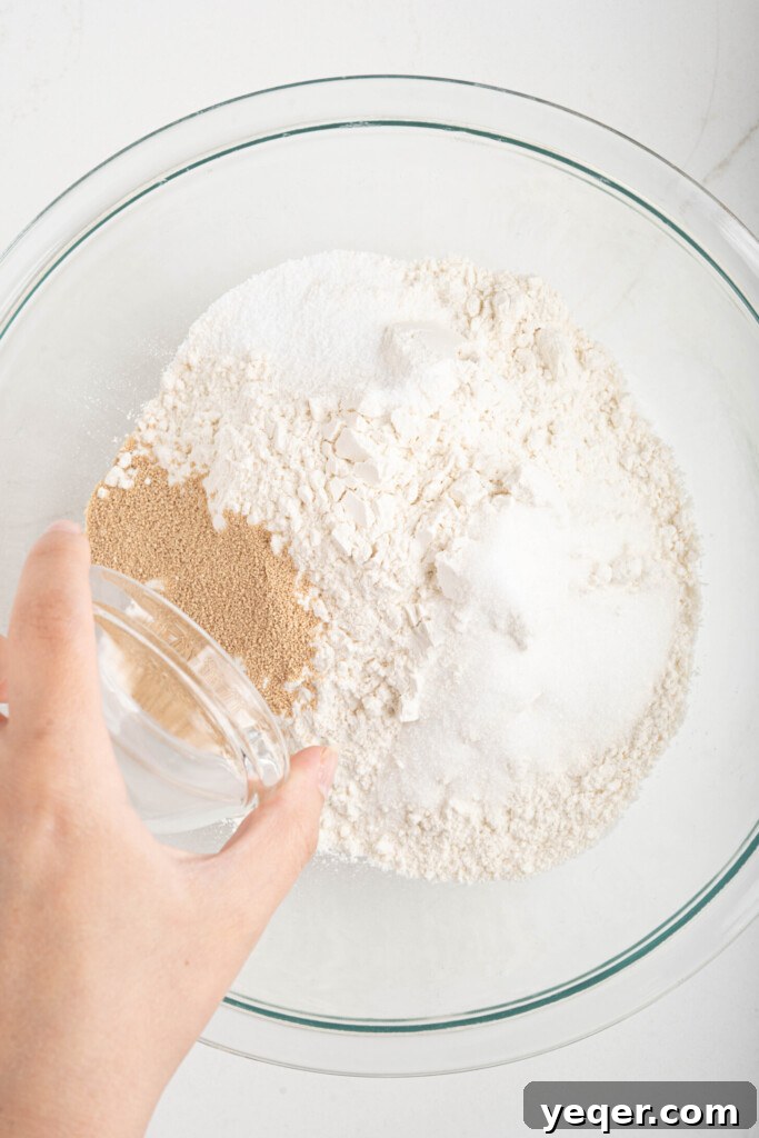 Sfenj: Moroccan Spongy Delights 4 A hand pouring active dry yeast into a bowl containing all-purpose flour.