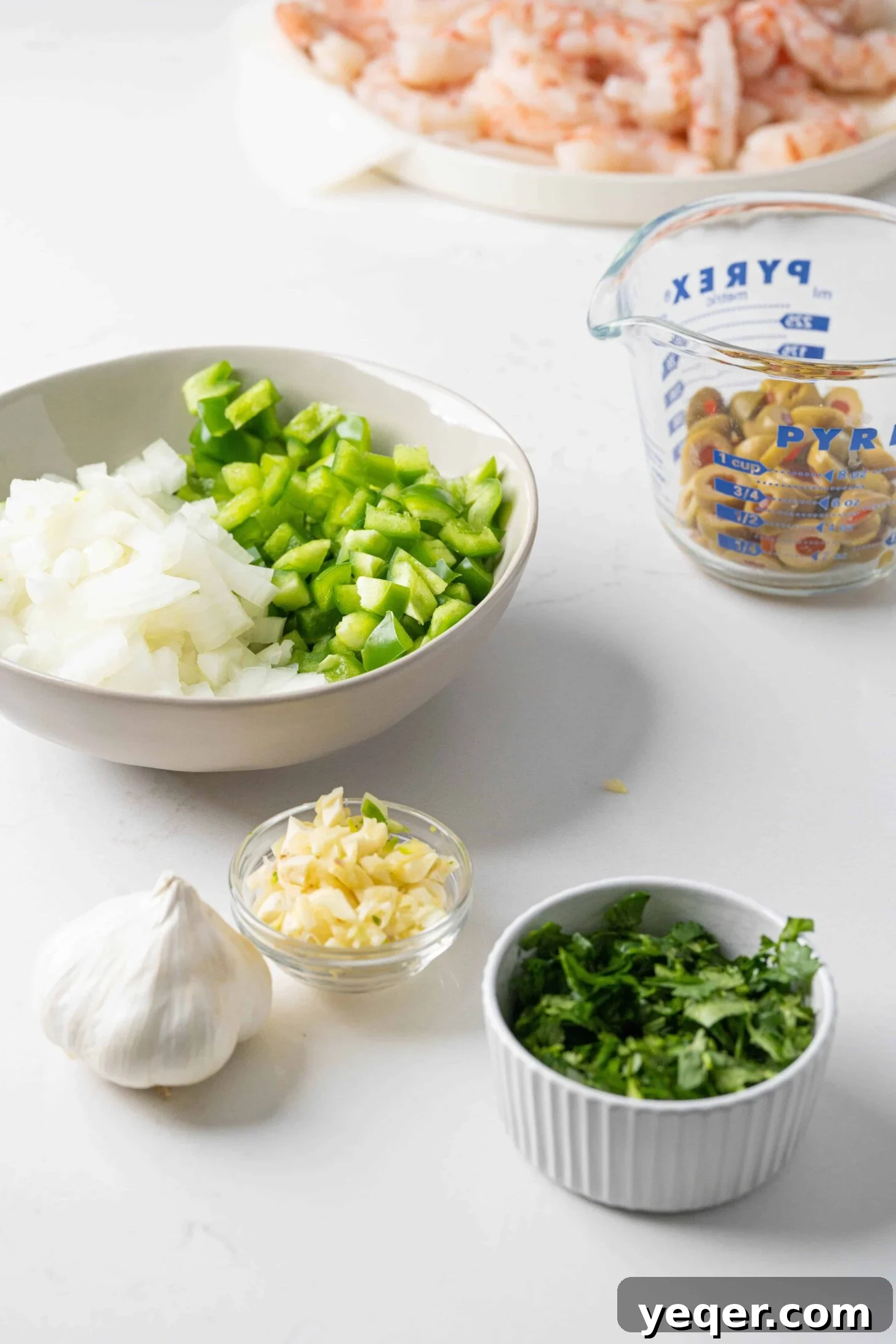 Savory Simmered Shrimp 3 Fresh ingredients laid out for making stewed shrimp, including onions, bell peppers, garlic, olives, tomato puree, cilantro, and raw shrimp.