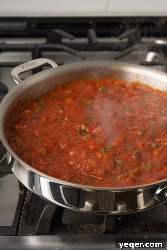 Savory Simmered Shrimp 5 A pot of rich tomato-based sauce simmering with olives and spices.