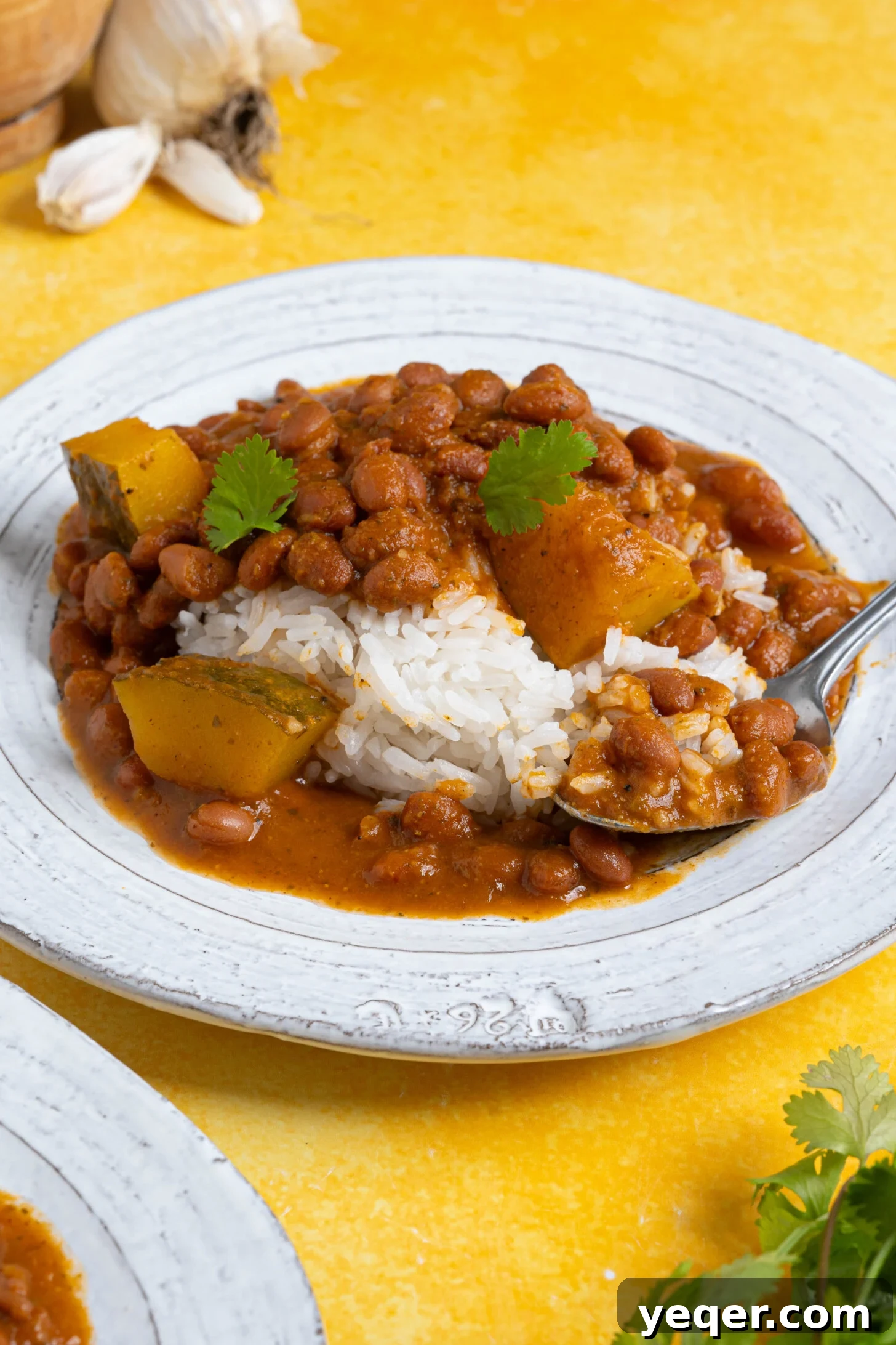 Hearty Puerto Rican Bean Stew 3 A hearty plate of Habichuelas Guisadas served alongside perfectly cooked white rice, garnished with fresh cilantro.