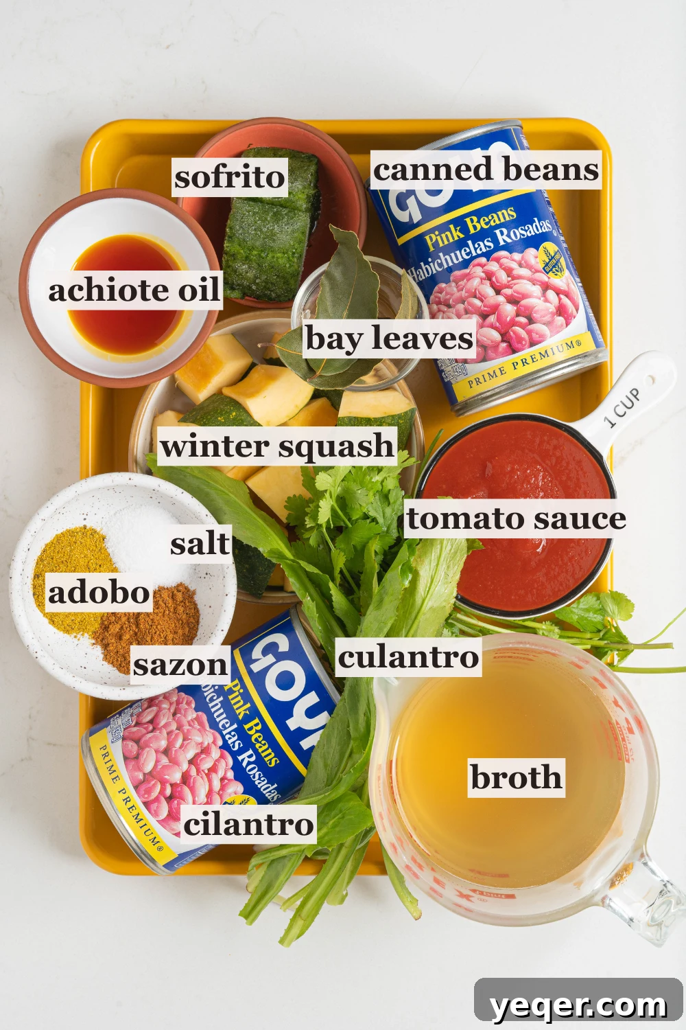 Hearty Puerto Rican Bean Stew 4 Assorted bowls showcasing key ingredients for Habichuelas Guisadas: vibrant sofrito, rich tomato sauce, olive oil, and a selection of spices including sazon and adobo.