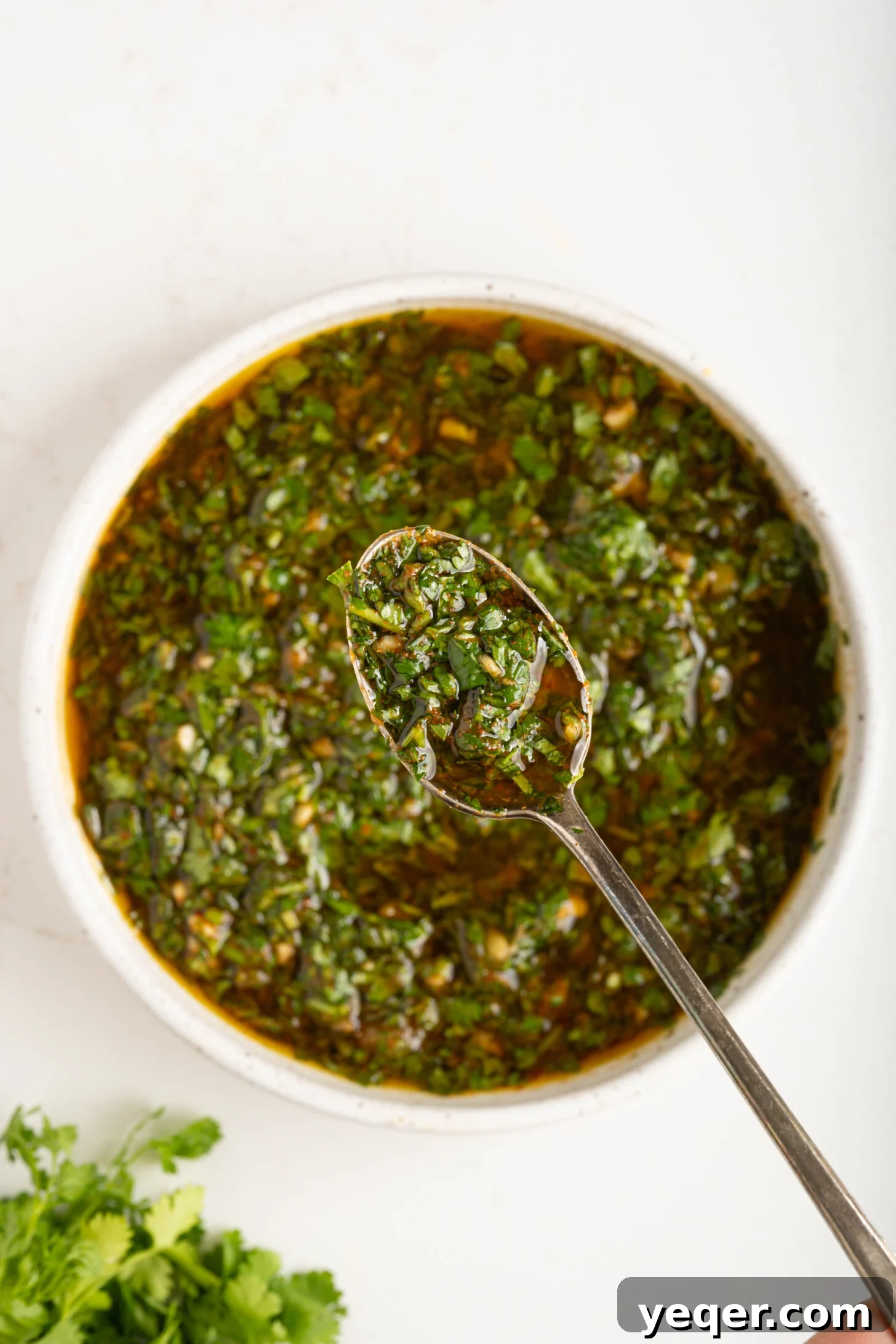 A close-up of a spoon laden with rich, green chermoula marinade, ready to be enjoyed or added to a dish.