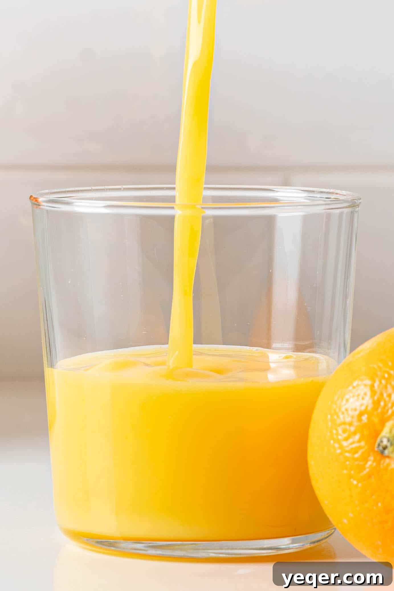 Hand-Pressed Orange Delight 2 A glass of freshly squeezed orange juice, vibrant and inviting, sits on a rustic wooden surface, ready to be enjoyed.
