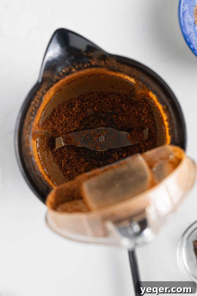 10 Minute Moroccan Coffee Bliss 4 Whole star anise pods and coffee beans being poured into a coffee grinder, symbolizing the first step of blending spices with beans.