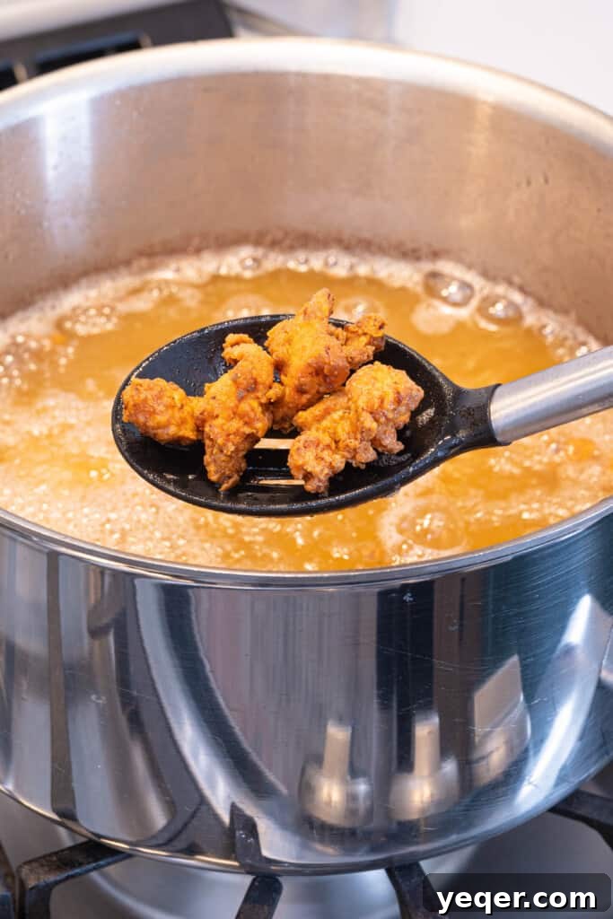 Golden Puerto Rican Chicken Chicharrones 6 Fried chicken being removed from a frying pan