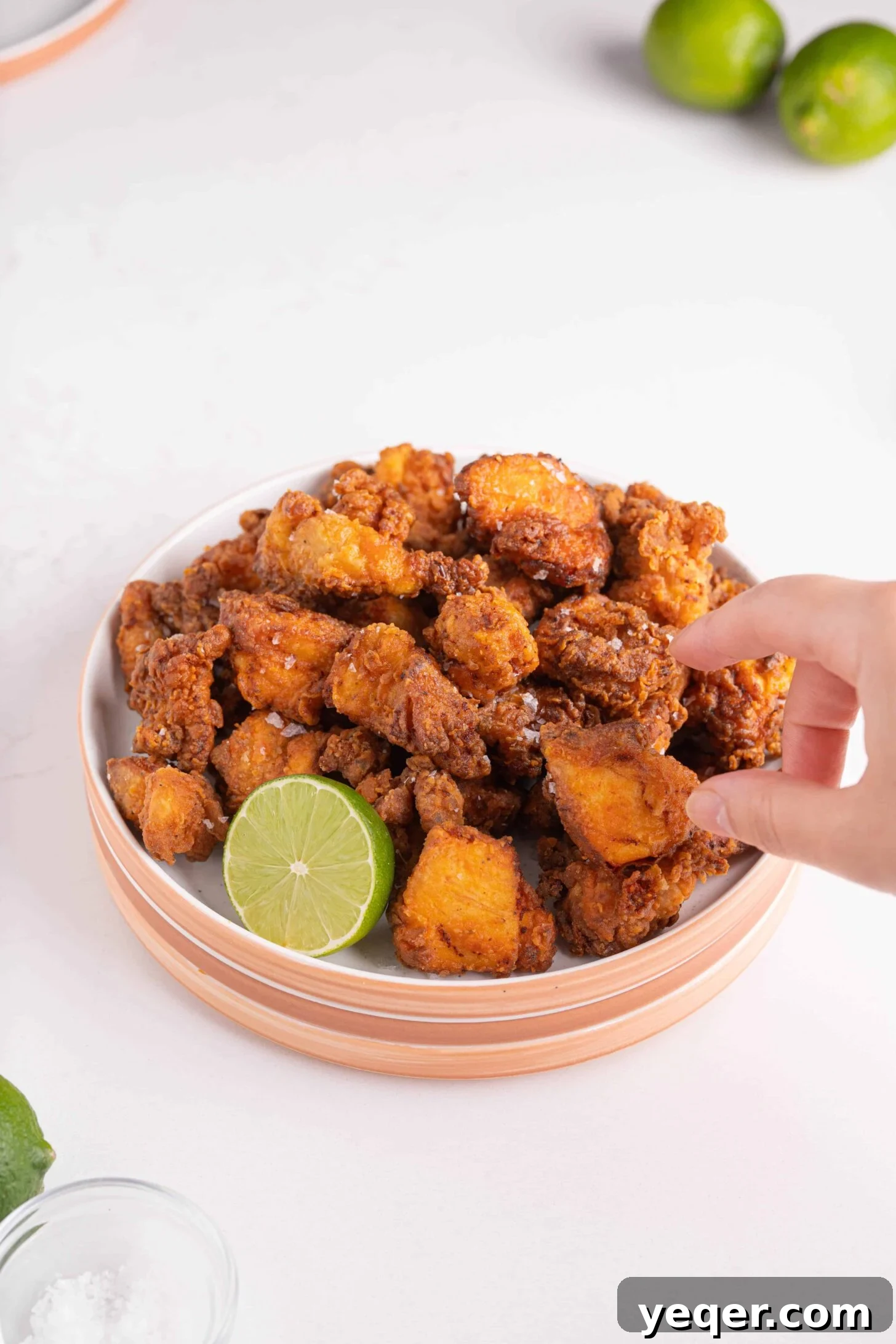Golden Puerto Rican Chicken Chicharrones 7 A hand grabbing a piece of crispy Puerto Rican fried chicken