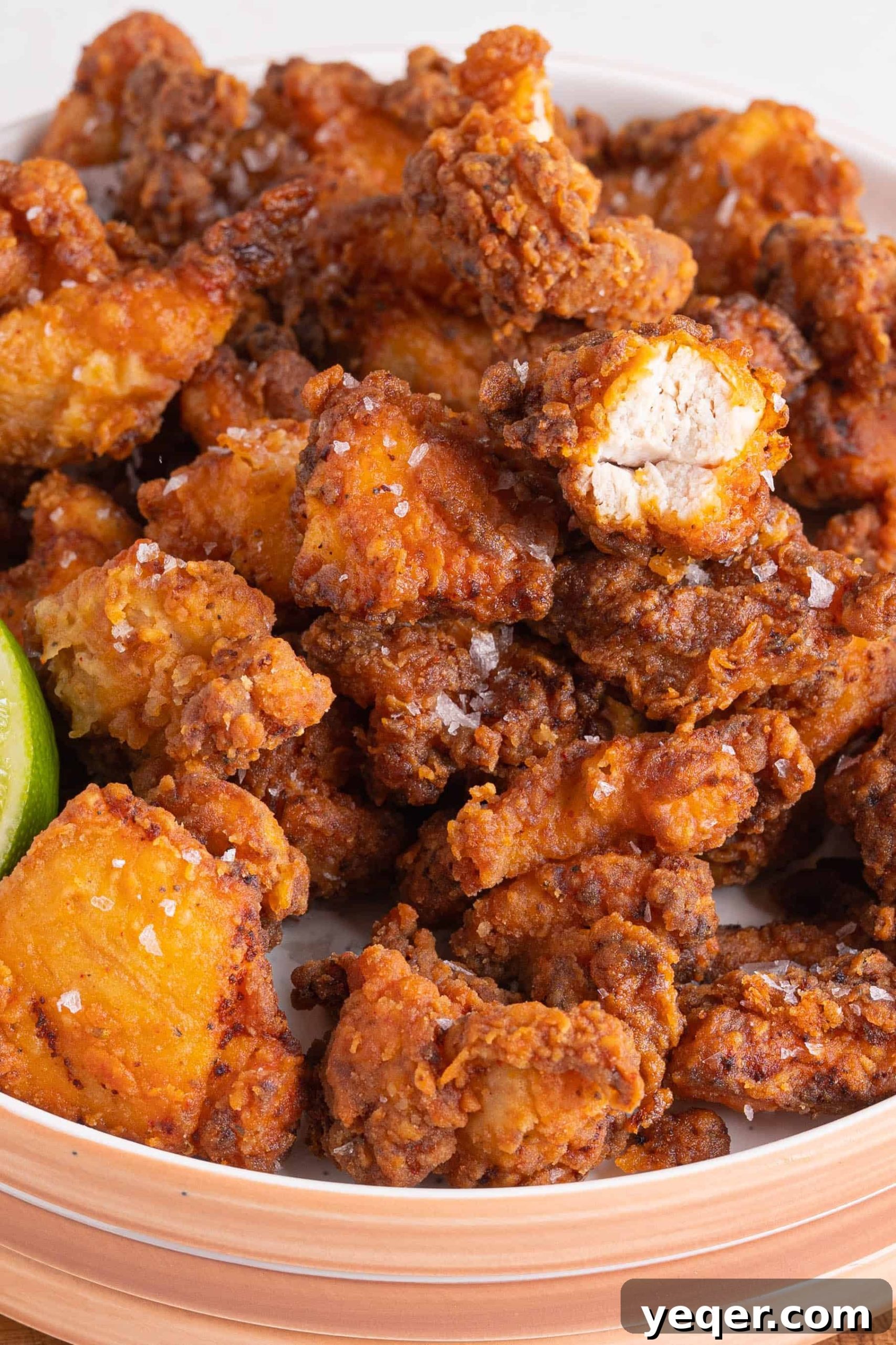 Golden Puerto Rican Chicken Chicharrones 9 A beautifully arranged plate of Puerto Rican fried chicken with lime wedges