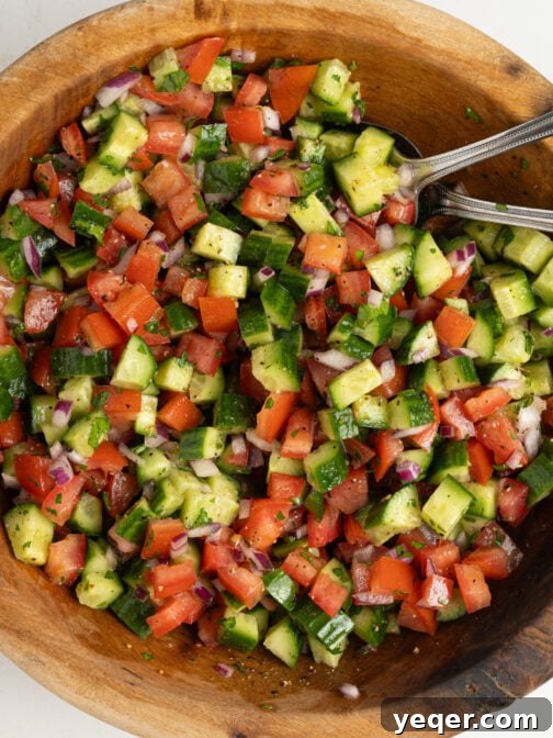 A bowl of vibrant Moroccan cucumber tomato salad, garnished with fresh herbs.