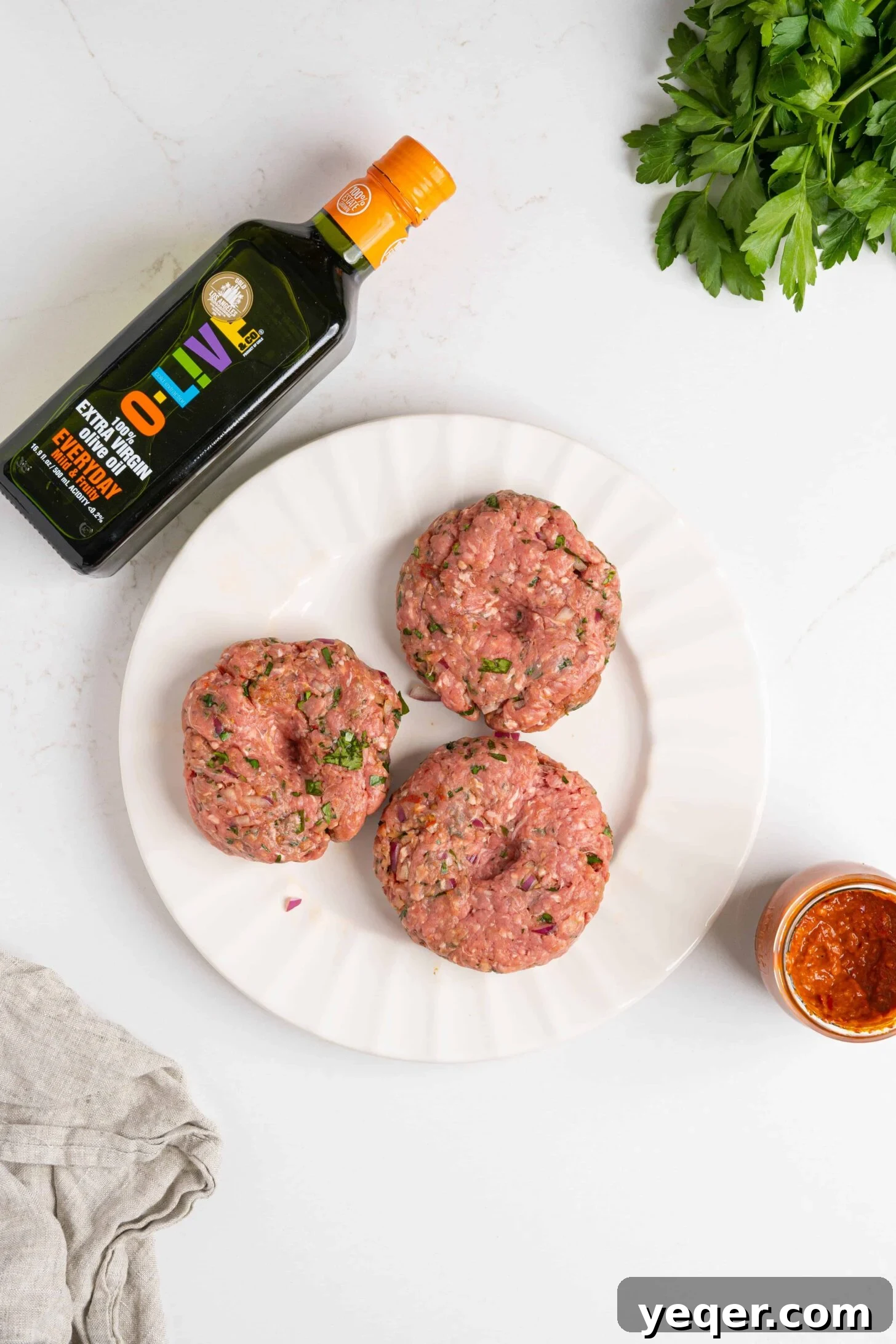 Spicy Harissa Burgers 3 Hand-formed harissa burger patties, seasoned and ready for grilling, showcasing their rich color and texture.